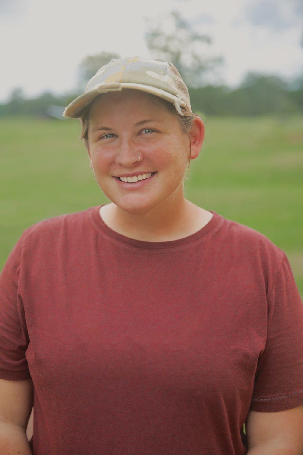 A woman wearing a baseball cap smiles at the camera.